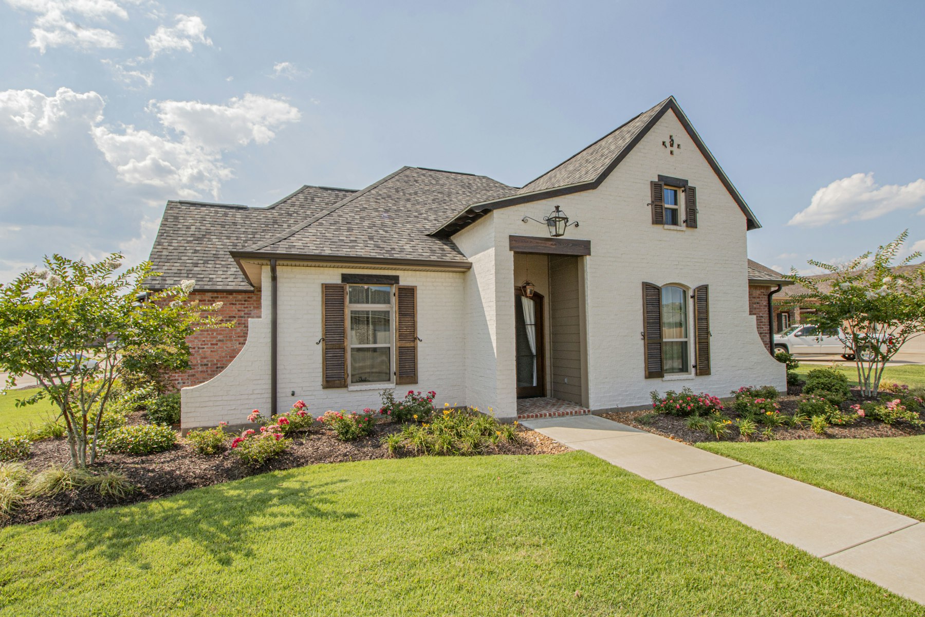 White and brick single-family home with manicured lawn