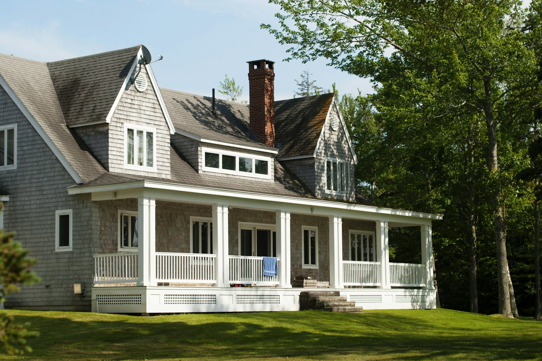 Shingled cottage with covered porch and well-kept lawn